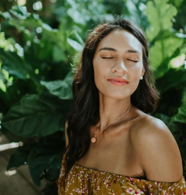 Model with closed eyes in green plants